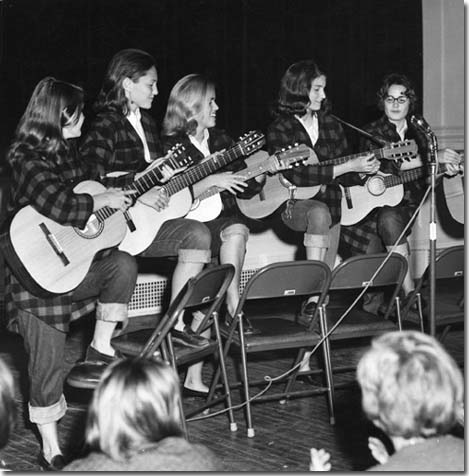 a group of women play acoustic guitars for a crowd