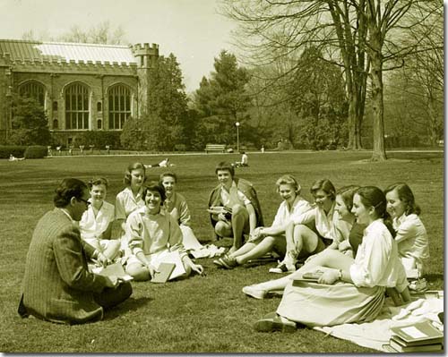 Teacher and students sit on the lawn outside Rockefeller Hall for a lecture
